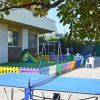 Area giochi per bambini all'aperto con scivolo, altalena e tavolo da ping pong.