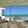 Una terrazza con tavoli e sedie, vista mare e cielo blu.