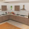 Cucina moderna con mobili in legno chiaro, doppio lavello, forni e cappa.