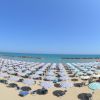 Vista di una spiaggia affollata con ombrelloni bianchi e blu.