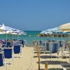 Una spiaggia con ombrelloni blu a righe e sedie a sdraio sulla sabbia.
