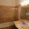 Bagno con lavabo e specchio, vasca da bagno e lampada a parete accesa.