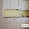 Cucina compatta con mobili chiari, lavello e forno a incasso.