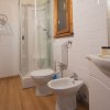 Bagno con doccia, lavabo, wc e bidet. Pavimento in legno e pareti piastrellate.