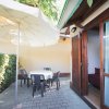 Terrazza con tavolo circolare, sedie nere e grande ombrellone bianco accanto a una porta-finestra.