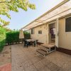 Terrazza di un bungalow con tavolo e sedie sotto una veranda, circondata da piante verdi.