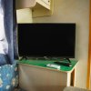 TV su un mobile accanto a una tenda blu e un divano con motivi.