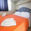 Letto matrimoniale con copriletto arancione e asciugamani bianchi piegati sopra.