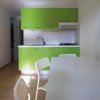 Cucina con mobili verdi, tavolo bianco e sedie traforate.