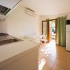 Cucina con lavello, tavolo bianco, porta aperta verso l'esterno.