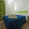 Camera con letto matrimoniale, lenzuola blu e tende verdi.