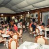 Un ristorante affollato con persone sedute attorno a tavoli bianchi sotto un soffitto coperto.