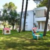 Giardino con casette giocattolo colorate e tavolini di plastica vicino a un edificio bianco.