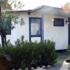 Un bungalow bianco e blu tra la vegetazione.
