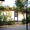 Casa bianca tra alberi e cespugli, strada ghiaiosa davanti.
