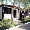 Bungalow con veranda e sedie, circondato da alberi.