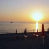 Tramonto su una spiaggia con ombrelloni chiusi.