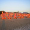 Spiaggia di sera con sedie a sdraio arancioni e ombrelloni chiusi.