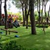 Un parco giochi all'aperto con altalene, scivoli e prati verdi tra gli alberi.