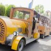 Un trenino turistico giallo con passeggeri a bordo su una strada alberata.