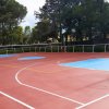 Campo da basket all'aperto, vuoto, con segnaletica colorata.