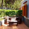 Patio con sedie di vimini, tavolino e cespuglio verde.