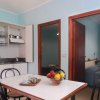 Cucina con tavolo, frutta e vista su due porte.