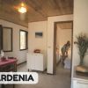 Interno di una casa con tavolo apparecchiato e una persona in una stanza adiacente.