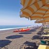 Spiaggia con sdraio sotto ombrelloni gialli.