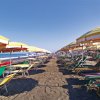 Una spiaggia con lettini e ombrelloni colorati.