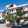Edificio bianco a tre piani con auto parcheggiate davanti.