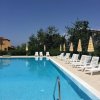 Piscina all'aperto con lettini bianchi e ombrelloni gialli.