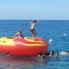 Persone su un gonfiabile rosso e giallo in mare.