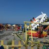Spiaggia affollata con gioco gonfiabile in fondo.