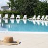Piscina con sedie a sdraio bianche e cappello di paglia in primo piano.