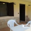 Veranda esterna con tavolo e sedie bianche.