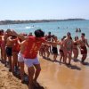 Persone sulla spiaggia in fila, vicino al mare.