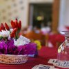 Centrotavola con fiori e peperoncini su tovaglia rossa.
