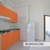 Cucina con mobili arancioni, fornelli e frigorifero.