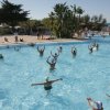 Persone che fanno acquagym in una grande piscina all'aperto.