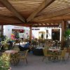 Area esterna di un bar con tavolini e sedie sotto una tettoia.