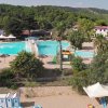 Piscina circondata da alberi e ombrelloni.