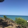 Sentiero costiero con vista mare e ringhiera di legno.