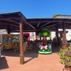Area coperta con sedie, giochi per bambini e piante.