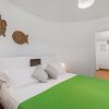 Camera con letto matrimoniale, copriletto verde, lampade e decorazioni a muro.