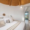 Camera luminosa con letto matrimoniale, soffitto in legno e vista mare.