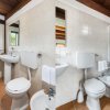 Un bagno con doccia, WC e lavandino. Pareti piastrellate e soffitto in legno. Asciugamani appesi.