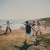 Persone che praticano yoga su un prato vicino al mare, in una giornata soleggiata.