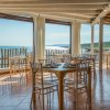 Ristorante con vista sul mare, arredato con sedie trasparenti e tavoli apparecchiati.