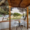 Veranda con tavolo, sedie e vista sul mare tra gli alberi.